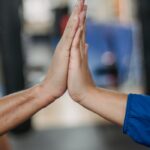 Crop faceless people clapping hands in room